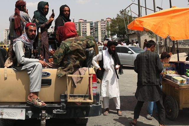8月17日，阿富汗塔利班成员在喀布尔街头向小贩购物。